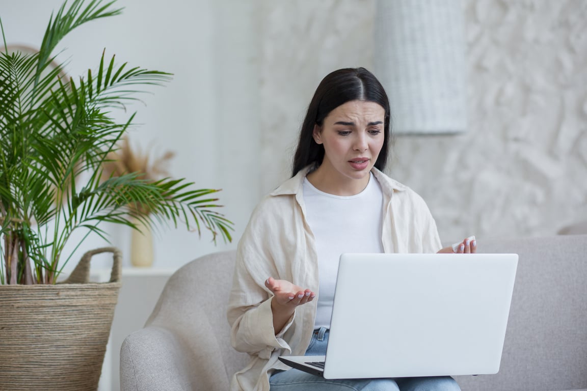 Online psychotherapy. A young worried woman is sitting at home with laptop